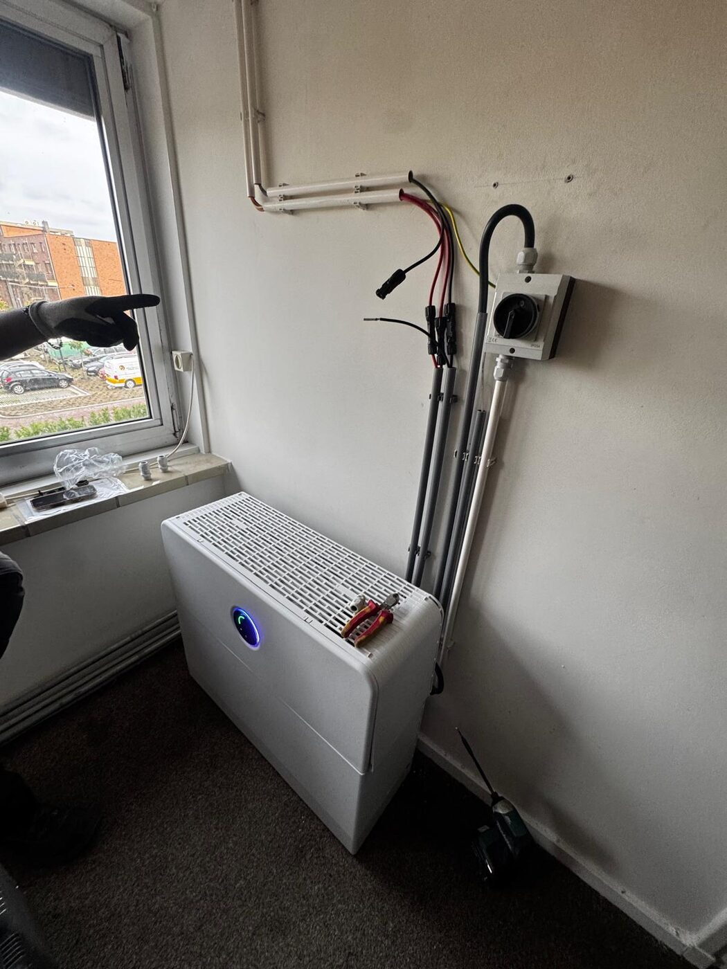 Geinstalleerde binnenunit met netjes weggewerkte koperleidingen en elektra aansluiting tegen de wand onder een raam