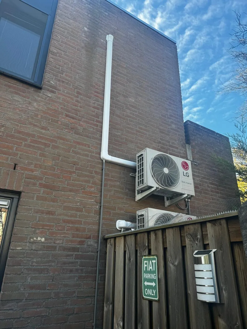 Buitenunit van een split-airco aan een gevel met nette leidingafwerking