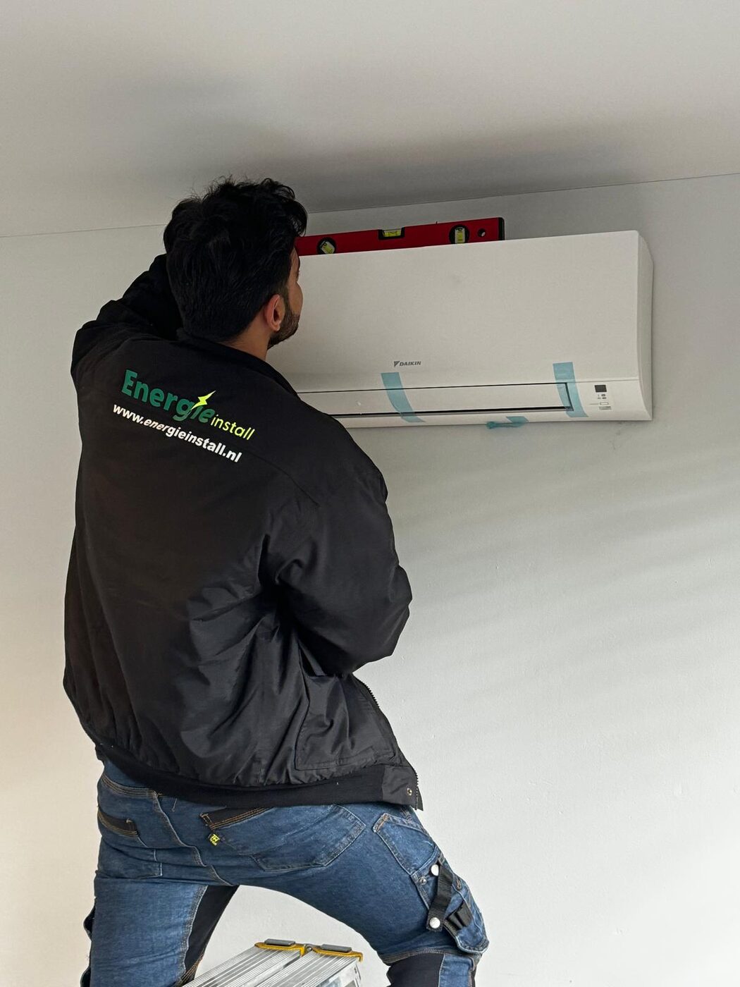 Energie Install monteur stelt Daikin airco binnenunit waterpas af tijdens montage aan de muur