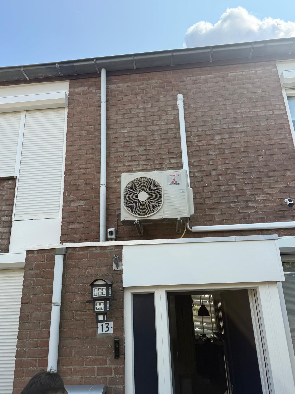 Airco-buitenunit aan de gevel boven de voordeur