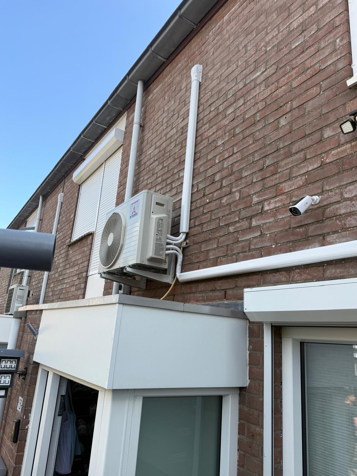 Airco-buitenunit met nette leidinggoten aan de gevel