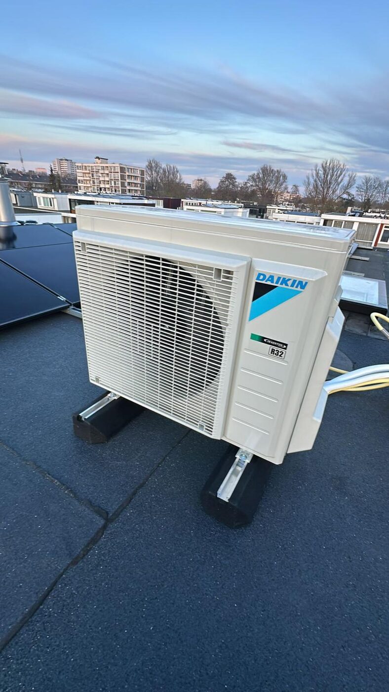 Daikin buitenunit van een lucht-water warmtepomp of airco geplaatst op een plat dak bij zonsondergang