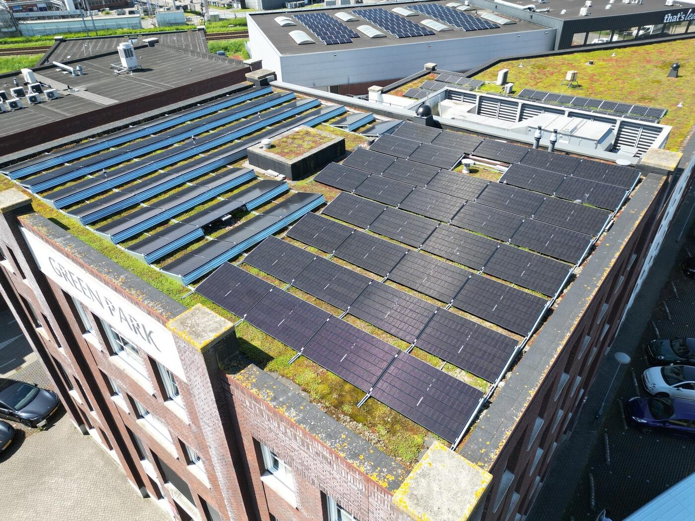 Luchtfoto van zonnepanelen op het platte dak van een bedrijfspand met groendak