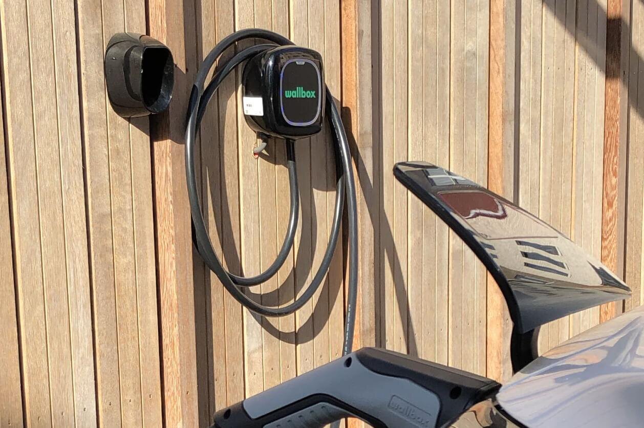 Laadpaal met laadkabel netjes gemonteerd aan een houten gevel