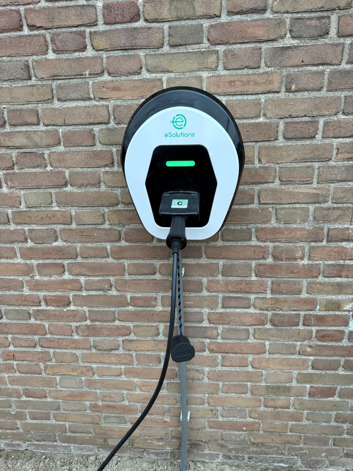 Wandlaadpaal met groene status-LED netjes gemonteerd aan een bakstenen gevel