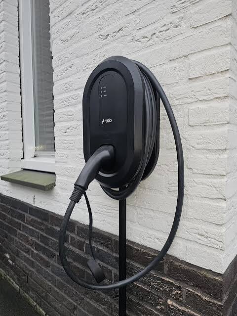 Wandlaadpaal met opgerolde laadkabel aan een wit geschilderde gevel