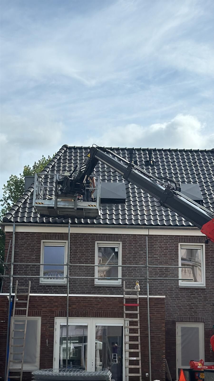 Zonnepanelen worden met een hoogwerker op een schuin dak geplaatst