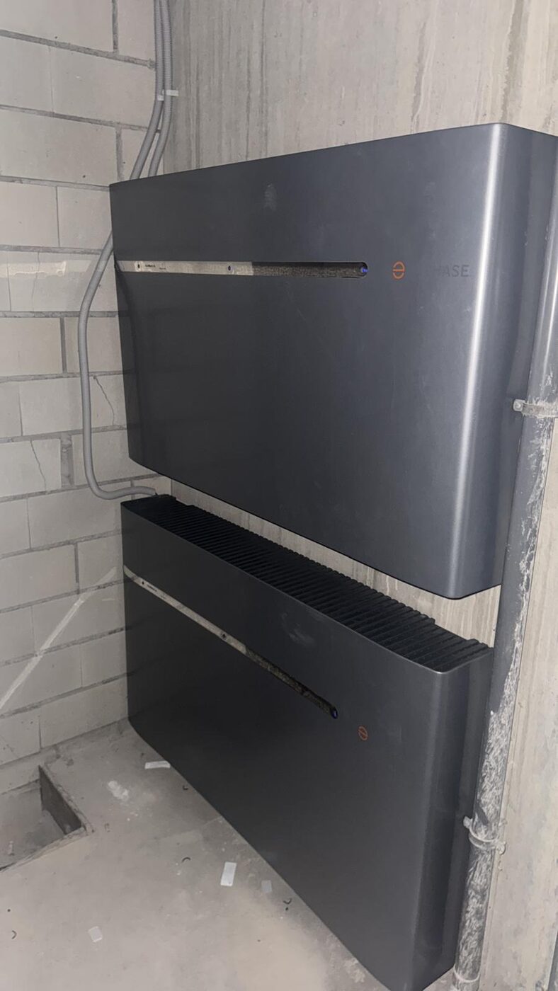 Twee gestapelde Enphase thuisbatterijen aan de wand gemonteerd in een technische ruimte