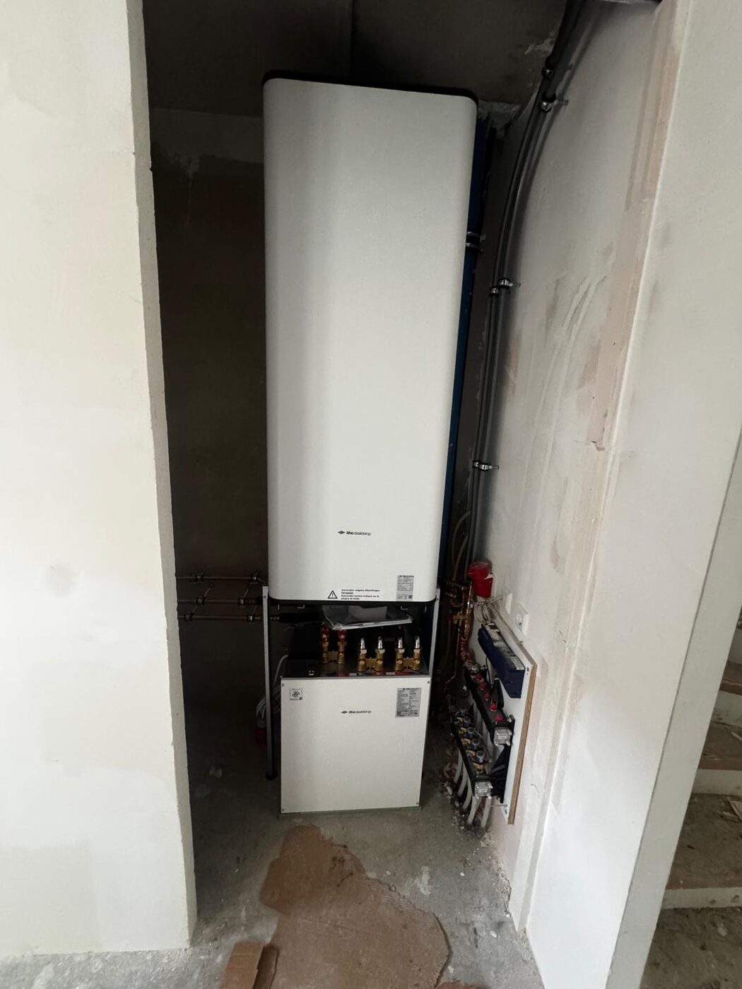 Binnenunit warmtepomp met boilervat en leidingverdeler in een technische ruimte