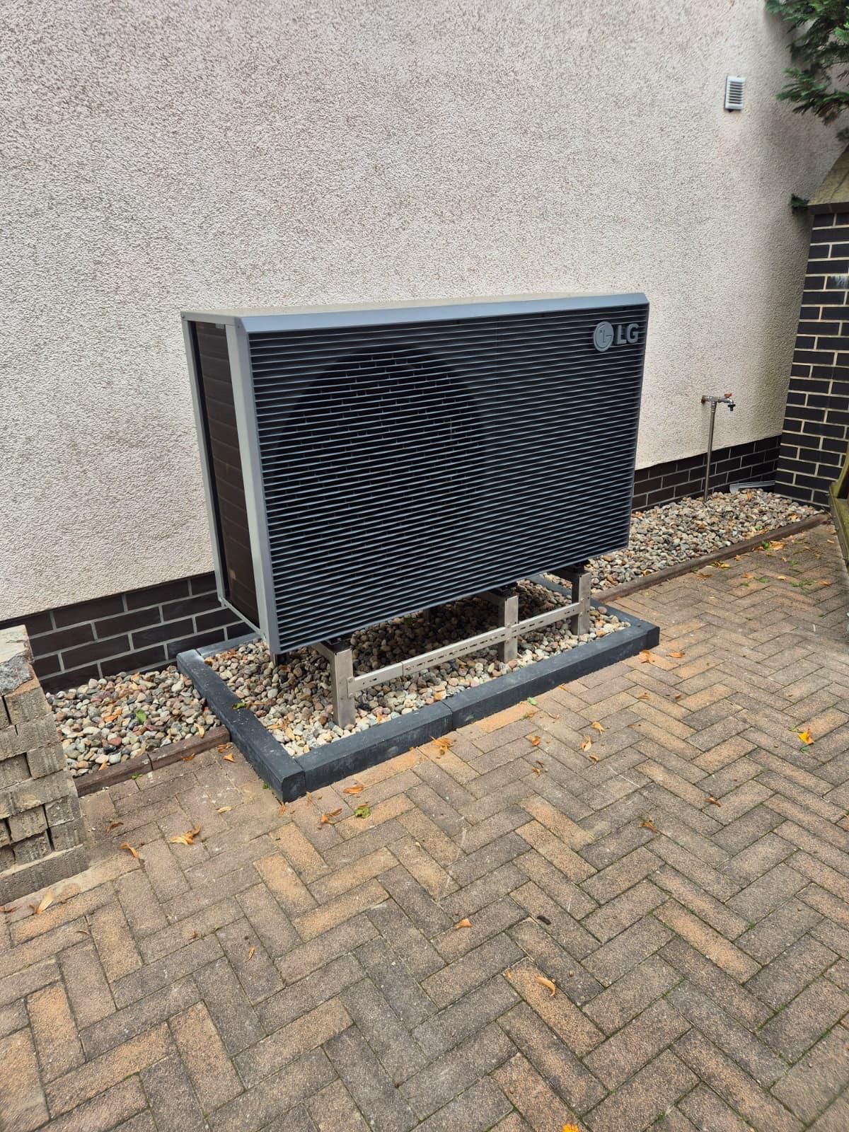 Warmtepomp-buitenunit op een betonnen voet naast een woning