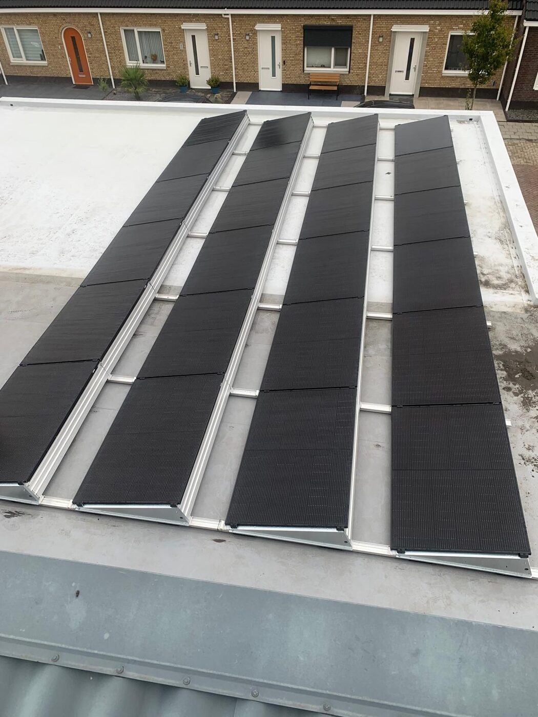 Zwarte zonnepanelen in rijen op een plat dak van een woning met aluminium montagerails