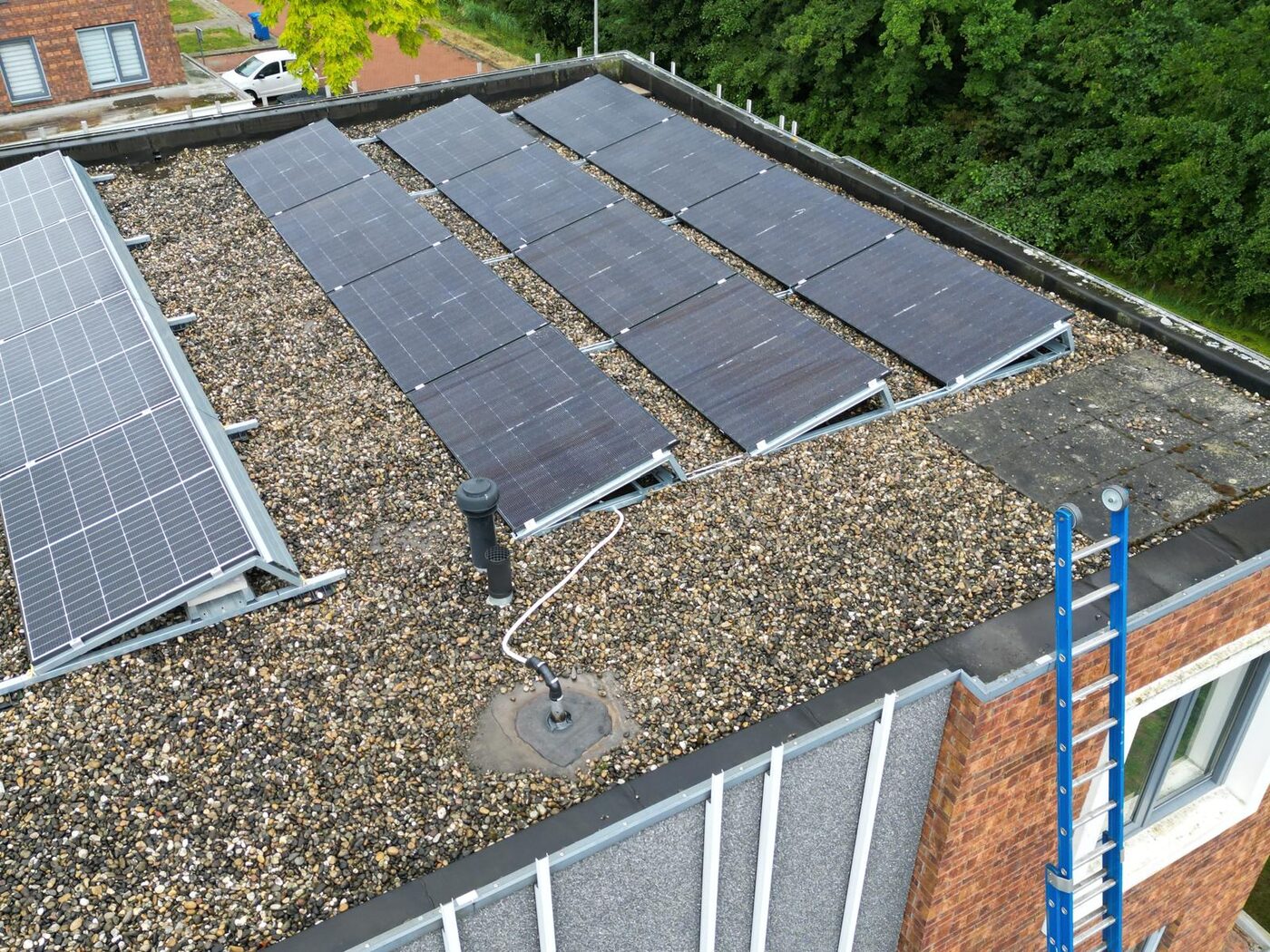 Zonnepanelen op een plat grinddak van een gebouw, gefotografeerd vanuit de lucht met drone